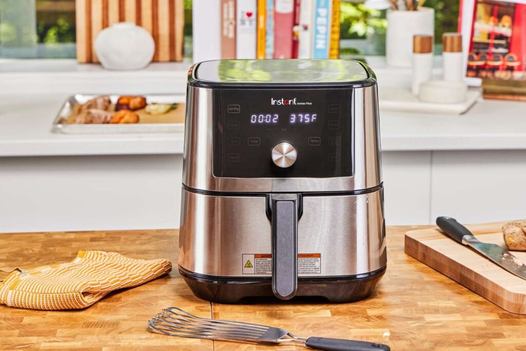 Instant Vortex Plus 6 Quart Air Fryer in stainless steel on a wooden kitchen counter, displaying a 375 degree temperature setting.