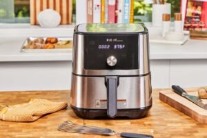 Instant Vortex Plus 6 Quart Air Fryer in stainless steel on a wooden kitchen counter, displaying a 375 degree temperature setting.